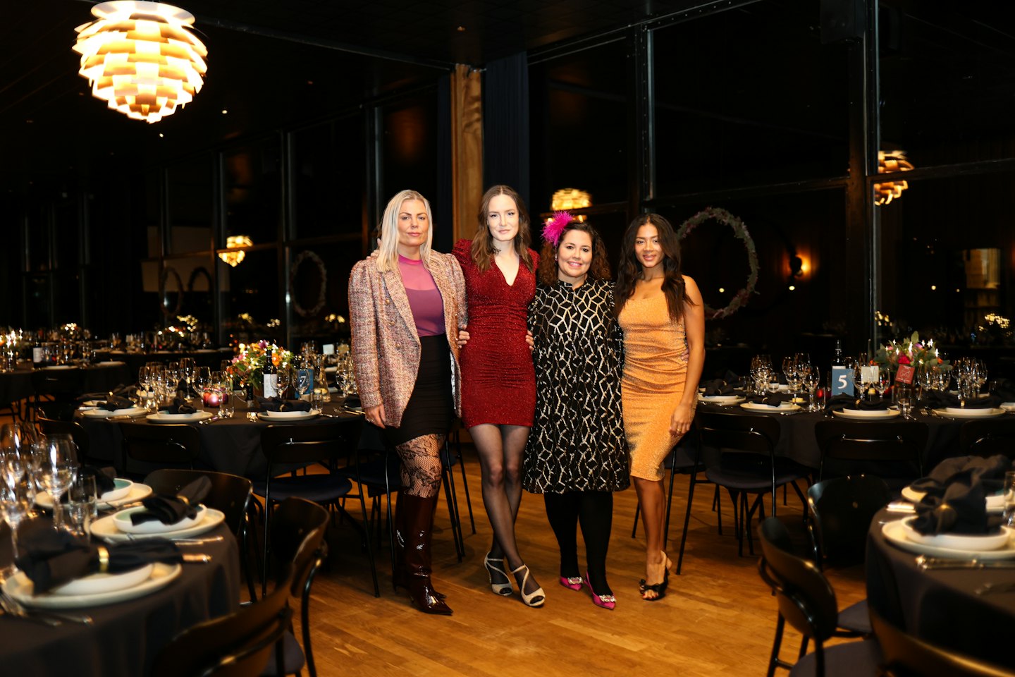 Vier Frauen in glitzernder Abendgarderobe posieren auf einem Gala-Abend.