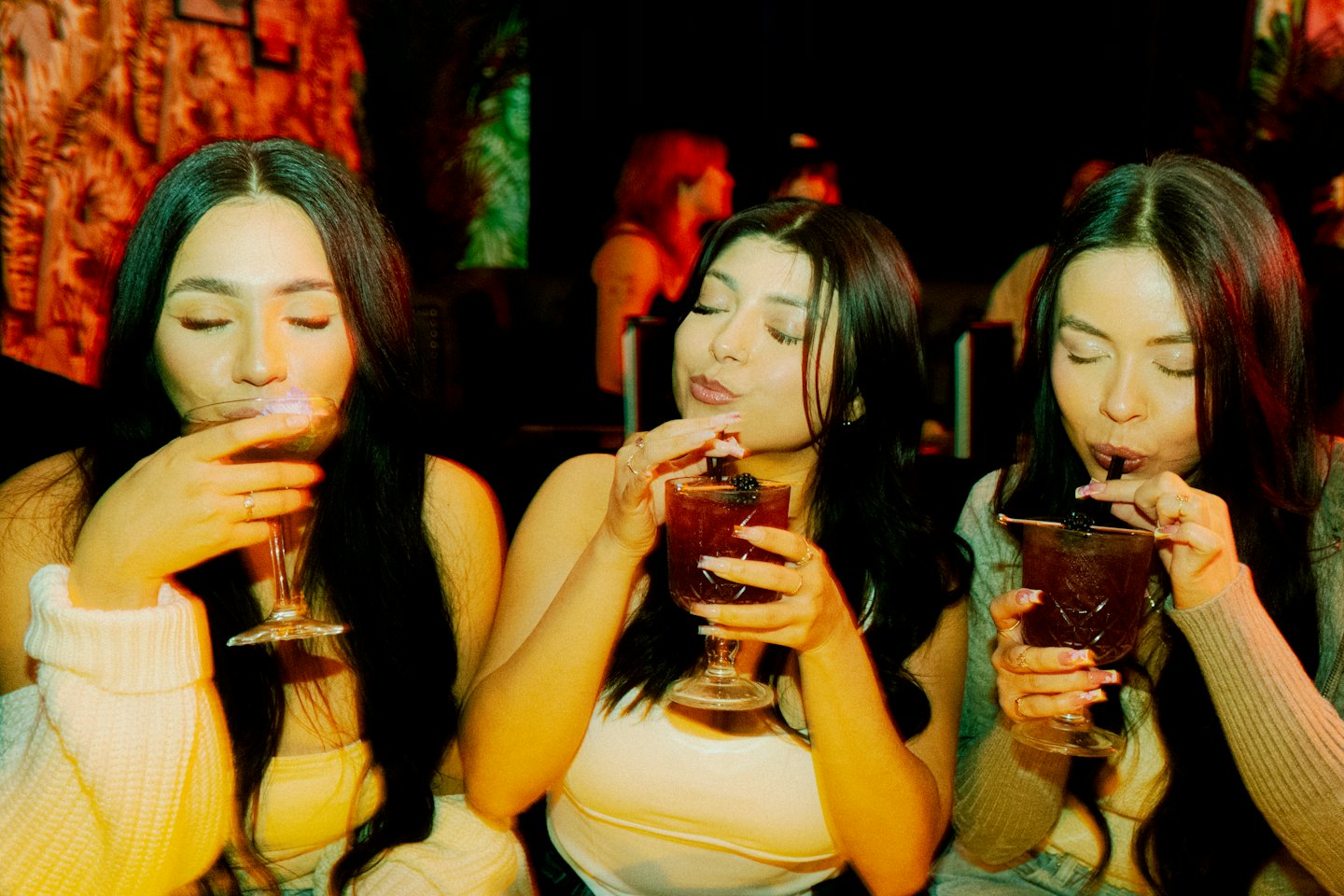 Drei Freunde trinken Cocktails an einer Bar.