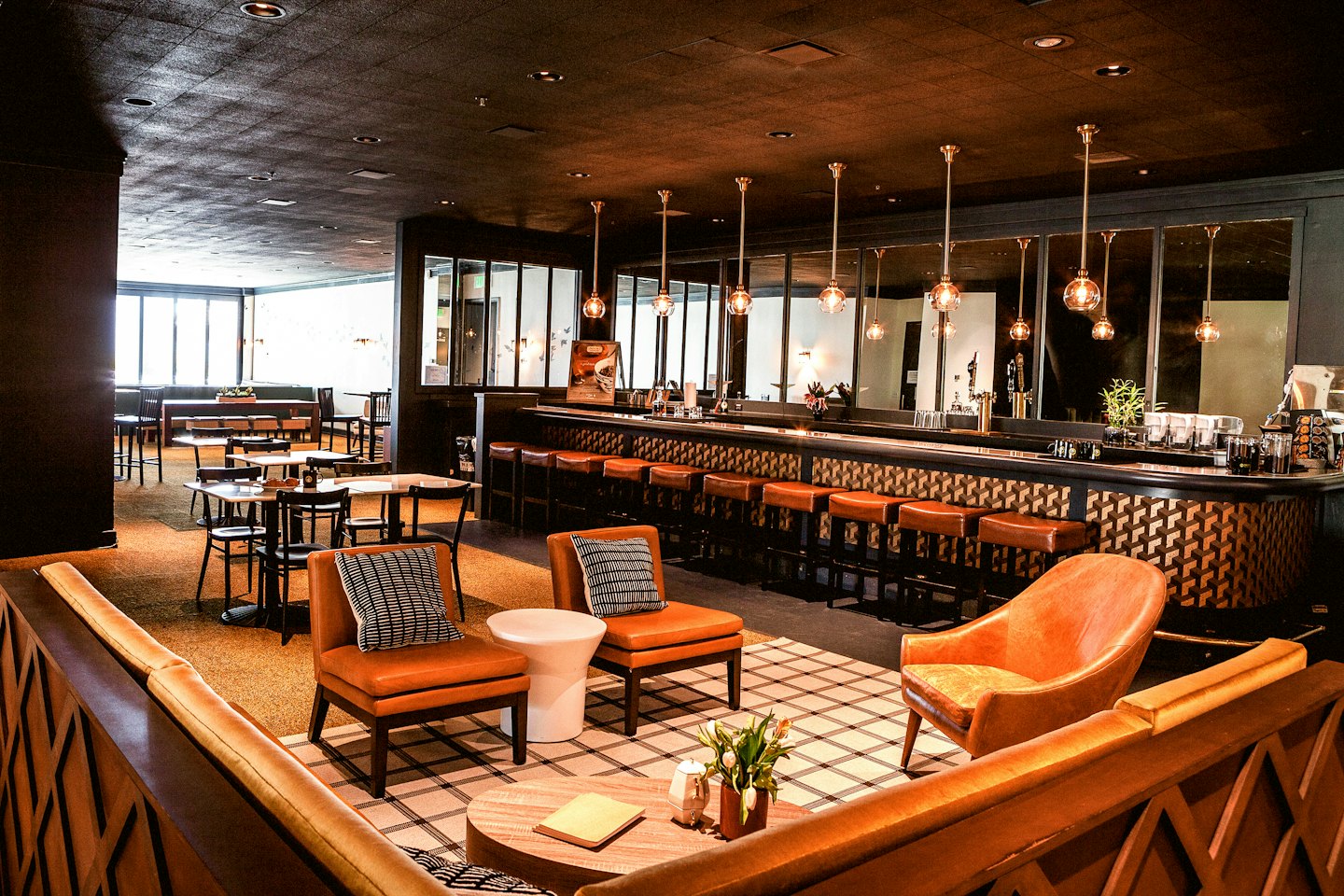 Gehobene Bar-Lounge mit braunen Ledersitzen und einer dunklen Holzbar.