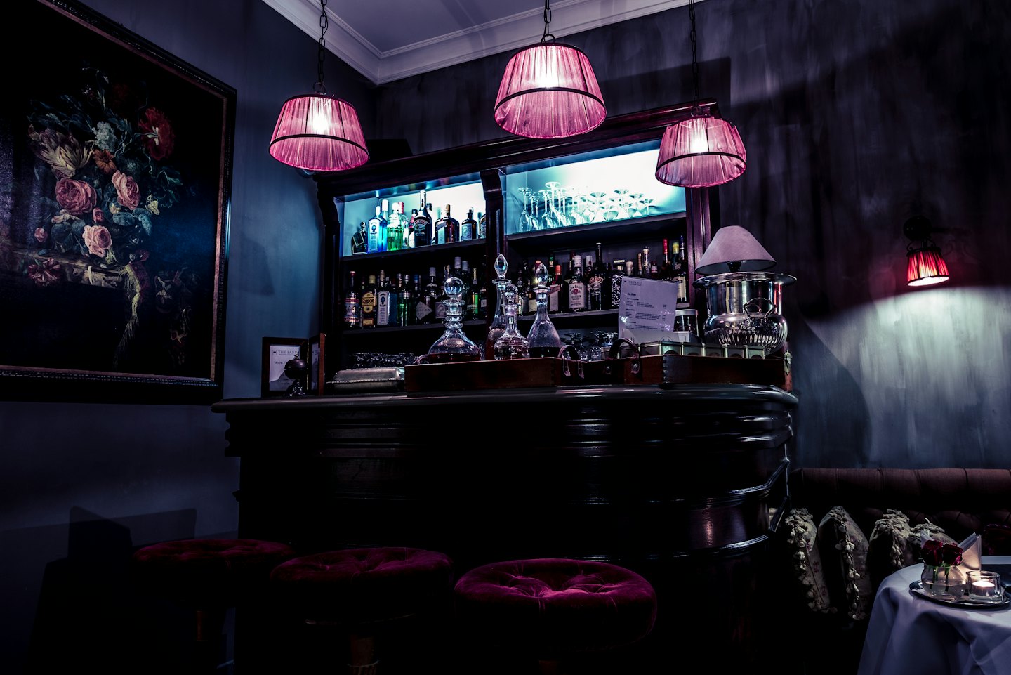 Luxuriöse Bar mit Samtstühlen und verzierten Pendelleuchten.